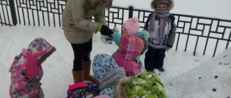 Children and a teacher in winter clothes look at the snow
