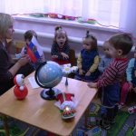 The teacher shows the children the flag of Russia